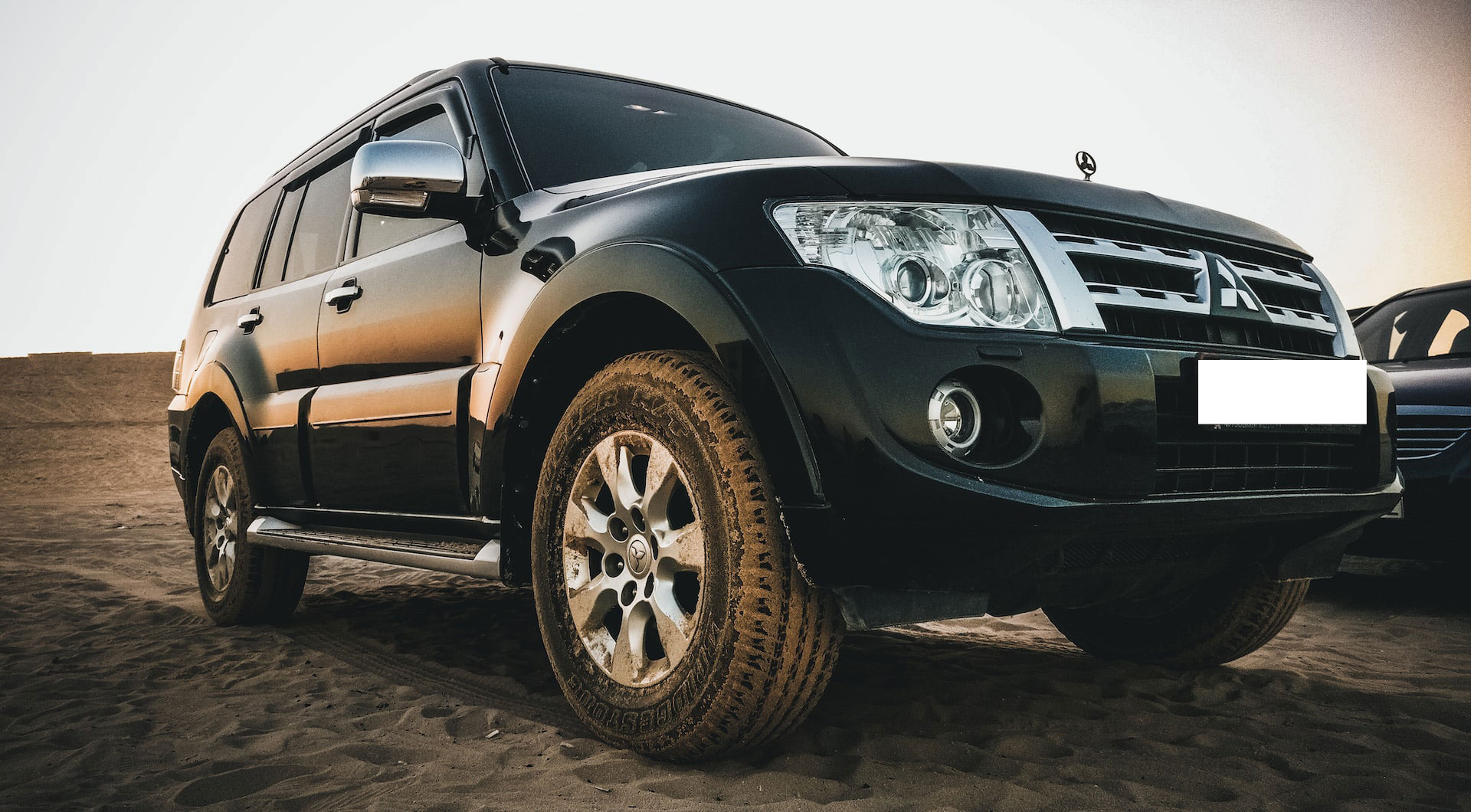 Black Mitsubishi car parked on the sand