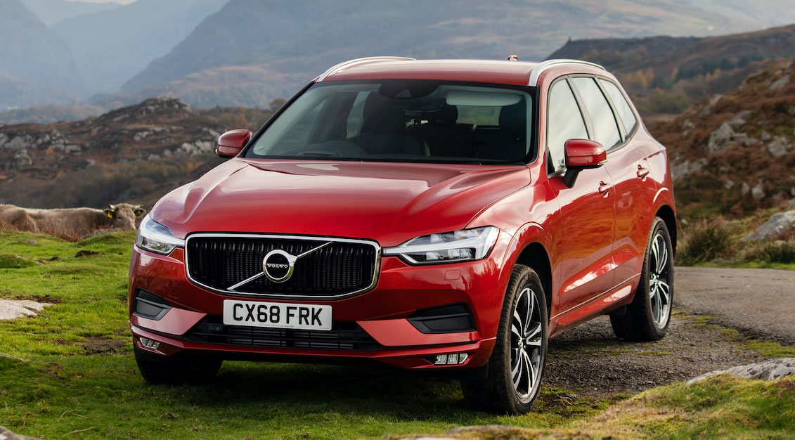 Red Volvo car in mountains near agriculture